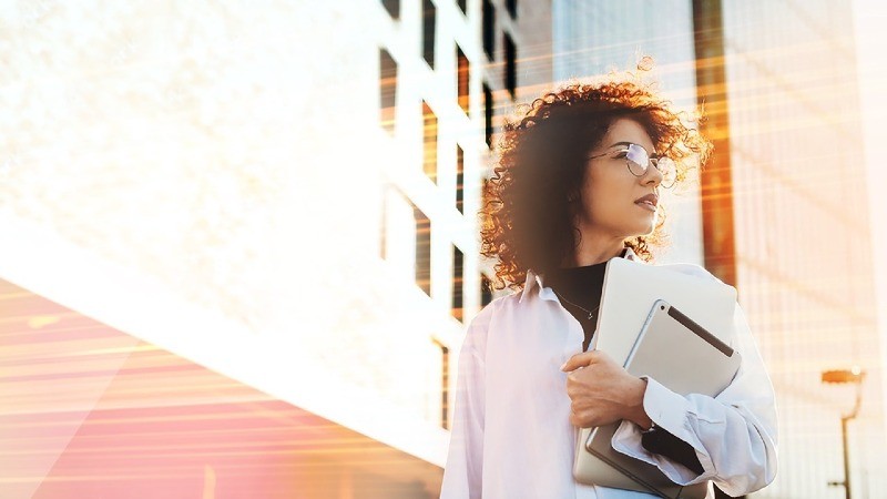 an office lady standing infront of the office building holding an ipad