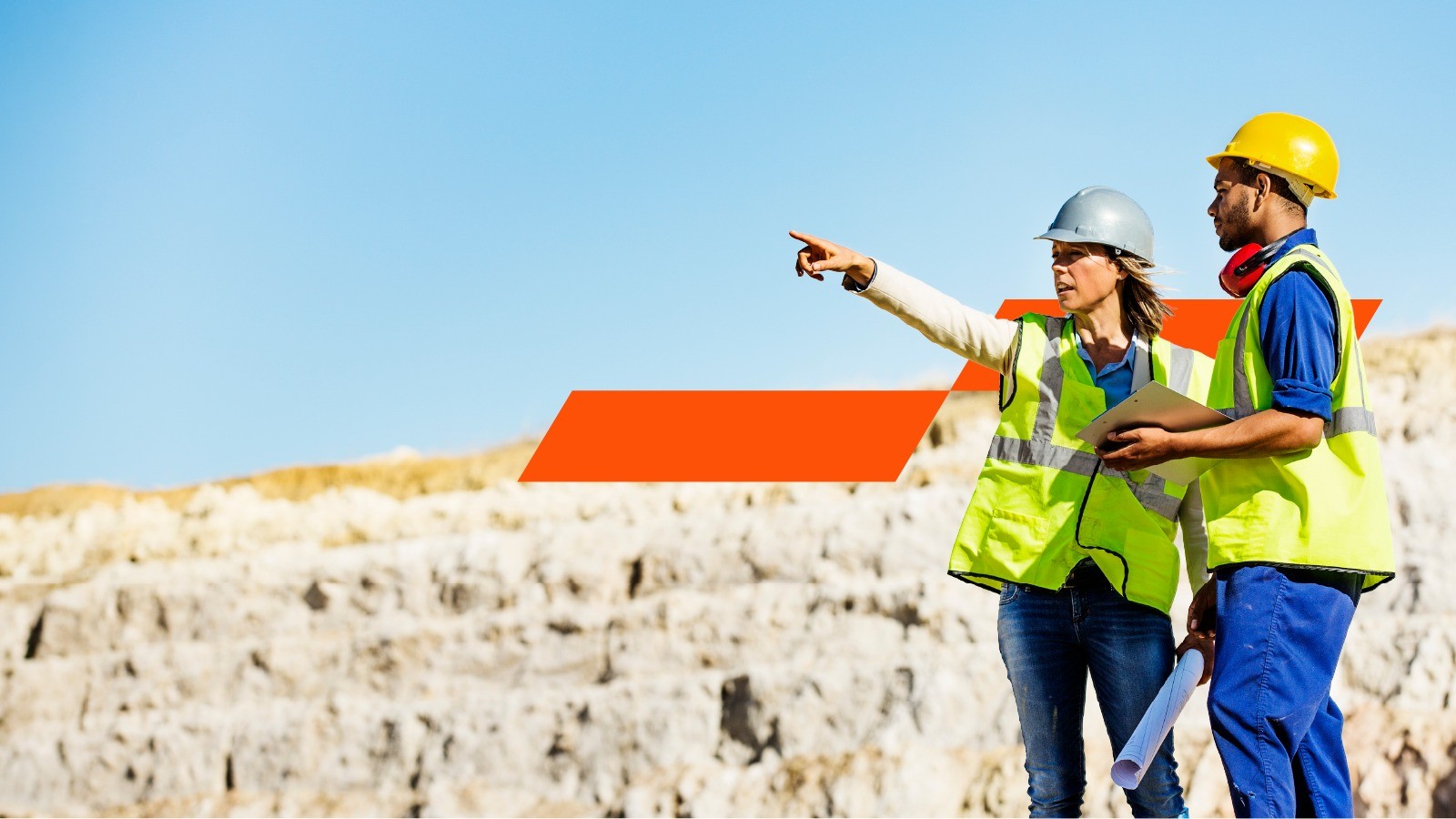 Two miners looking at a mining site wearing safety gears