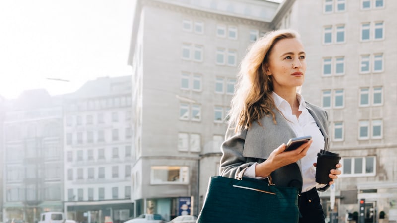 woman with phone and coffee looking forward and ahead