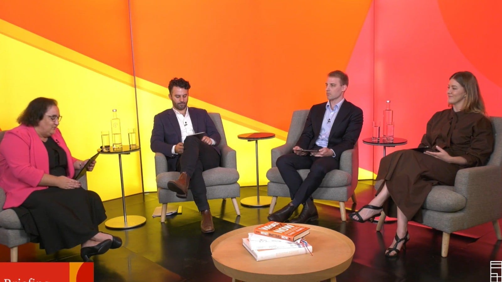 A panel of four professionals sits in a vibrant, orange-toned studio for a March 2026 PwC Tax Briefing to discuss current financial insights and regulatory updates.