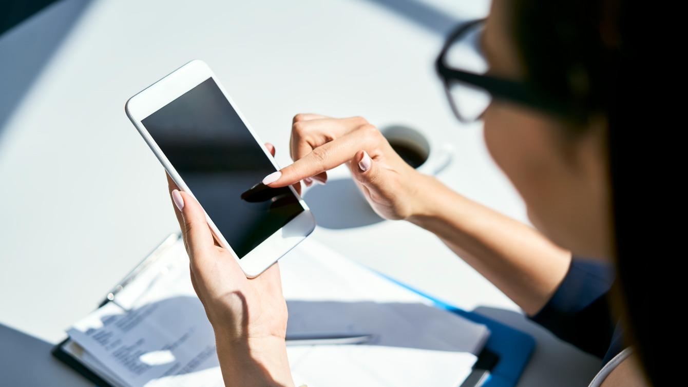 Woman ordering something on her smartphone while sitting with a coffee