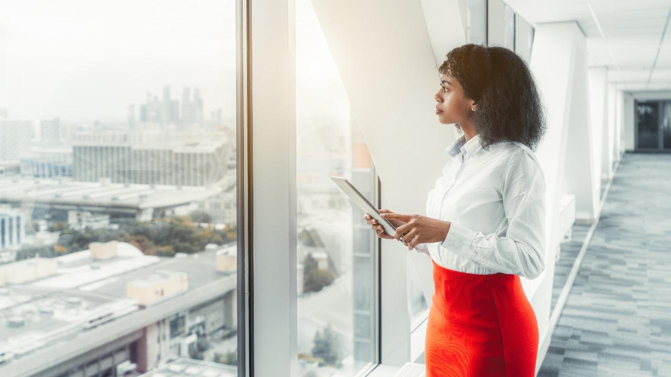 Woman standing at a large window in a skyscraper office