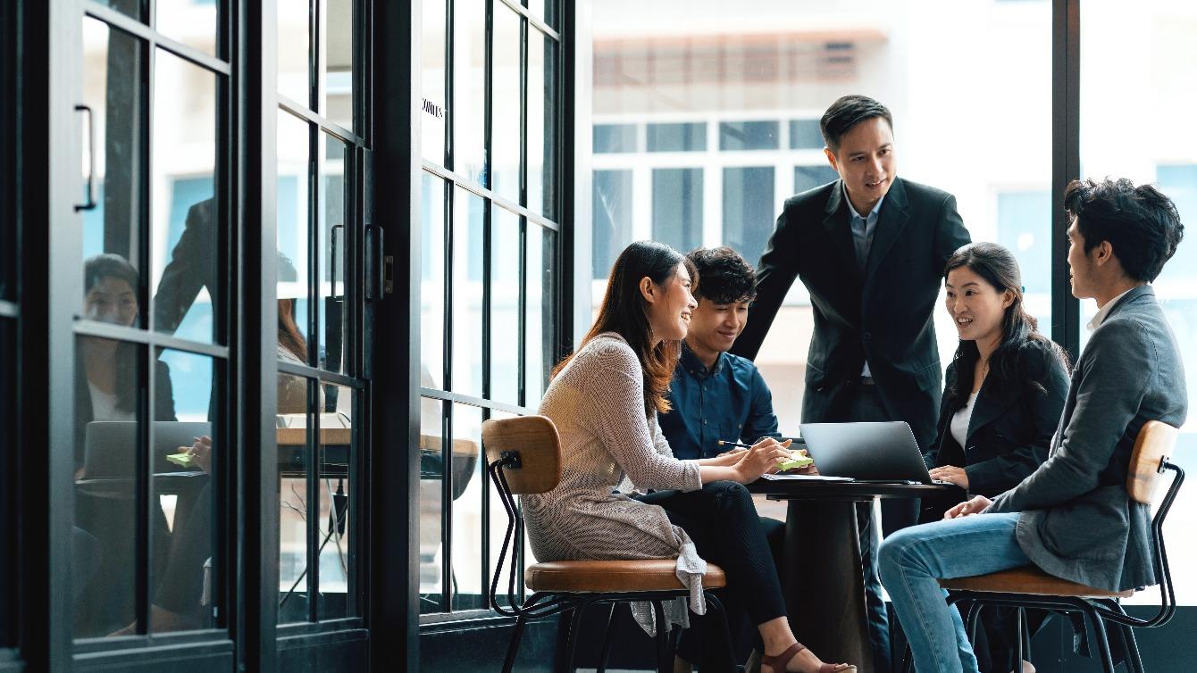 Group of workers chatting around a laptop on a desk